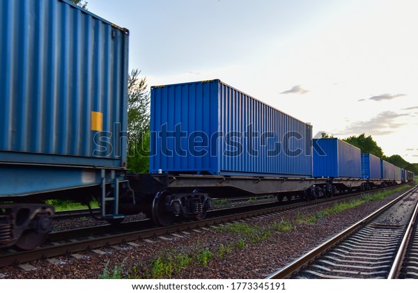 Cargo Containers Transportation On Freight Train By\
Railway. Intermodal Container On Train Car. Rail Freight Shipping\
Logistics Concept. Import - export goods from Сhina. Motion, Out of\
focus