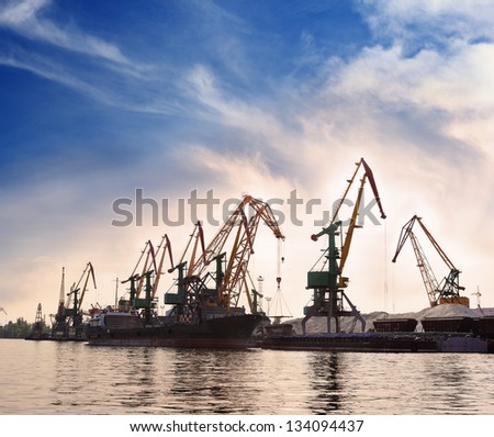 Cargo cranes in the dock by the water over blue sky