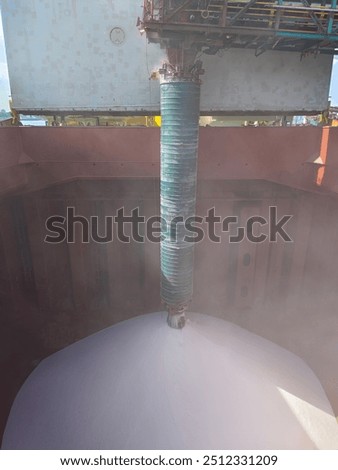 A cargo of potash in bulk is loading into a hold of cargo ship or bulk carrier.