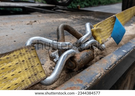 Cargo ratchet straps with metal hooks on the side of a flat bed truck used to secure heavy loads in order to transport them safely