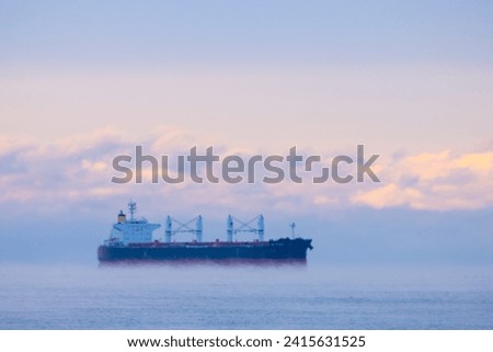 Cargo ship at blue hour, with sea smoke, blurred by heat haze