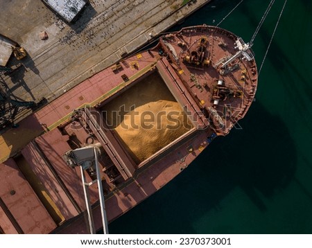 cargo ship or bulk carrier loaded to the brim with grain is preparing for departure, working sailors on deck are completing work, aerial view
