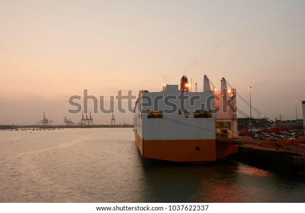 Cargo\
ship for car transportation in the port at\
sunset.