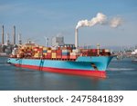 Cargo Ship With Containers In Industrial Trade Port With Smokestacks From Chimney And Wind Generators