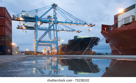 Cargo ship loading containers by night - Powered by Shutterstock