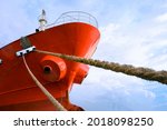 Cargo Ship moored at port with mooring Rope against white clouds on blue sky background