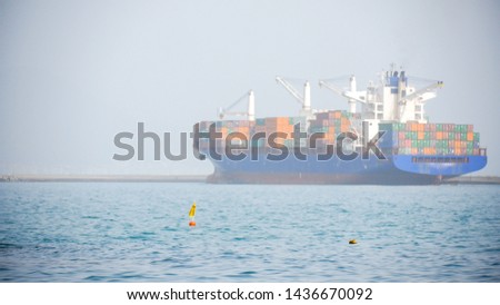 Cargo ship with multiple containers floats in the sea far away