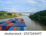 Cargo ship navigating the panama canal, passing under the centennial bridge, a symbol of global trade and logistics