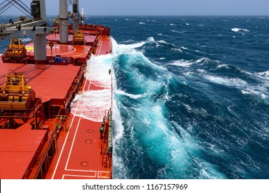 Cargo ship rolling in stormy sea. Huge waves under blue sky in Indian Ocean