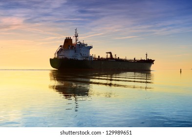 Cargo Ship Sailing Away Against Colorful Sunset