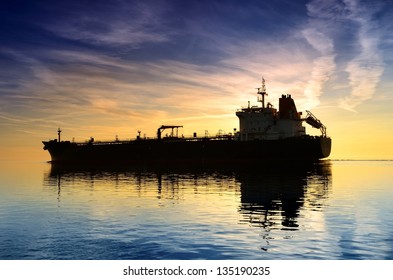 Cargo Ship Sailing Away Against Colorful Sunset