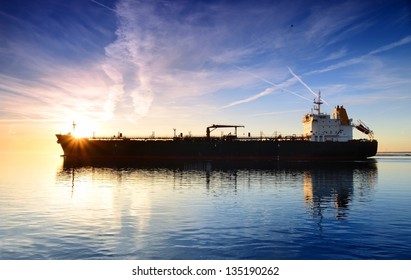 Cargo Ship Sailing Away Against Colorful Sunset