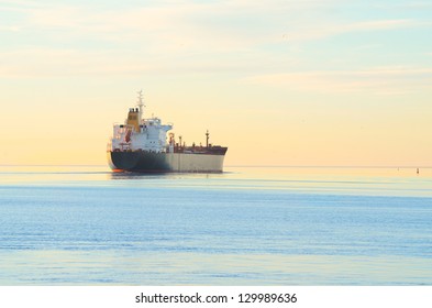 Cargo Ship Sailing Away At The Colorful Sunset