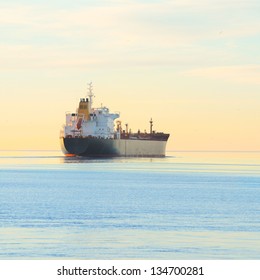 Cargo Ship Sailing Away At The Colorful Sunset