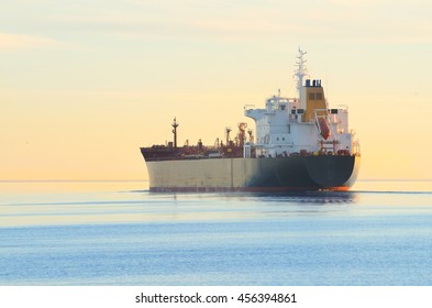 Cargo Ship Sailing Away At The Colorful Sunset