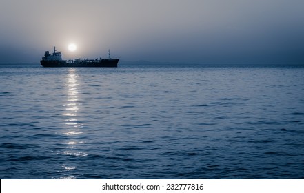 Cargo Ship Sailing With Full Moon Rising Above It