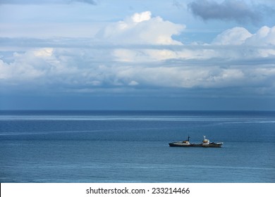 Cargo ship sailing in the sea on the backdrop of a cloudy sky - Powered by Shutterstock