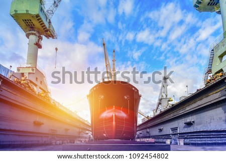 Cargo ship under repair sandblasted and painting at floating dry dock in shipyard