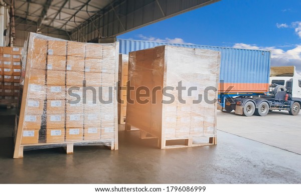 Cargo shipment loading for truck. Logistics and\
transportation. Cargo freight truck. Delivery service. Warehouse\
docks. Stacked package boxes on pallet waiting to load into cargo\
container truck.