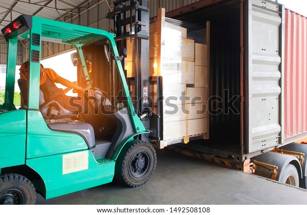 Cargo shipment loading for truck. Warehousing\
logistics and transportation, forklift driver loading cargo pallet\
into container truck . 