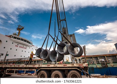 Cargo Shipment Of Steel Coil Being Loading Or Discharging By The Workers Stevedore Man In The Port Under Handle By The Ship Crane With The Lorry Trailer Transport Delivery Under Hooks In Port Terminal