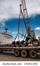 Cargo Shipment Of Steel Coil Under Loading Or Discharging By The Ship Crane Over Lorry Trailer Delivery Under Hooks In Port Terminal