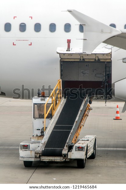 The cargo space\
of the aircraft is open. The vehicle with conveyor for freight\
standing beside an empty\
plane.