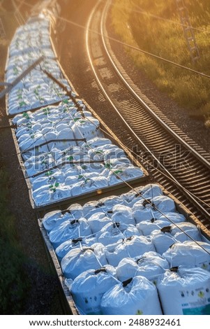 A cargo train is transporting large containers on the railroad tracks at sunrise