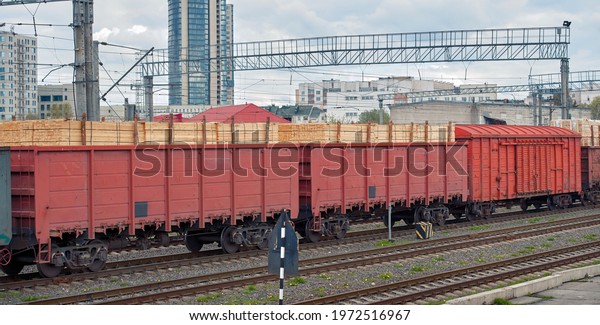 Cargo transportation by rail, container with\
timber. Wagons loaded with sawn timber, exporting timber and wood\
products. Railroad cars with wood\
boards.