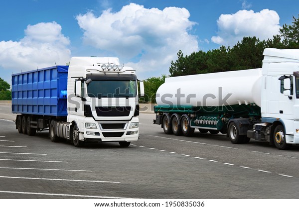 cargo transportation concept - two trucks is on a\
road, white tanker truck and blue container, blank space on a side\
view