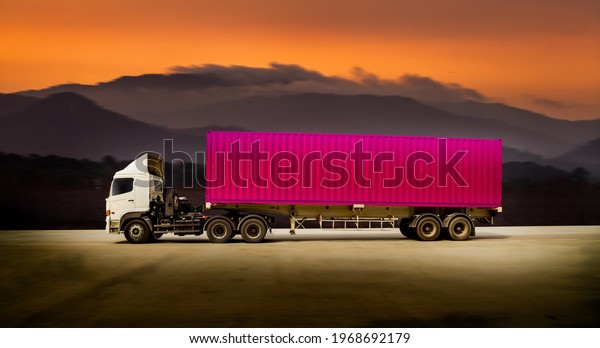 Cargo truck with heavy container speed on\
high way road to delivery logistic business with mountain and sun\
sky background.