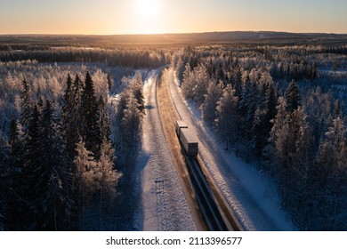 Cargo Truck On A Highway In Winter Landscape Against Sunset. Delivery And Transportation In Northern Europe.