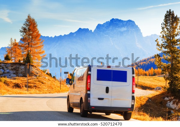 Cargo truck on the mountain highway with Alpine\
mountains Dolomites on a background. Delivery concept. Italy.\
Motion blur effect.