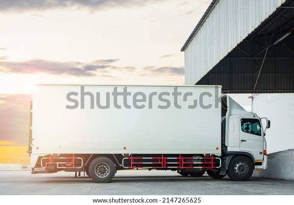 Cargo Trucks Parked at Warehouse with Sunset\
Sky. Shipping Container Trucks Freight Distribution. Lorry. Truck\
Transport Logistics.