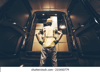 Cargo Van Delivery. Rear Cargo Doors Reloading. Construction Guy Talking Care of Fresh Supplies Delivery. Large Cargo Van with Many Cardboard  Boxes Waiting For Reload.