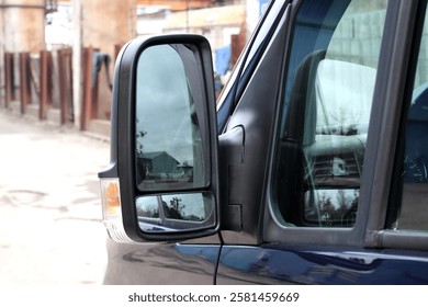 Cargo van side mirror with reflection in it. Black Rear-view mirror on a cargo van. Left external door car mirror.
