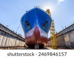 Cargo vessel in dry dock on ship repairing yard. Bulbous bow.