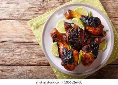Caribbean grilled chicken drumstick with lime and onions closeup on a plate on a table. Horizontal top view from above