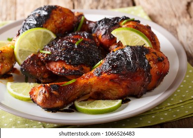 Caribbean grilled chicken drumstick with lime and onions closeup on a plate on a table. horizontal