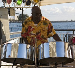 A Caribbean Musician Playing Steel Drums With The Ocean In The Background.