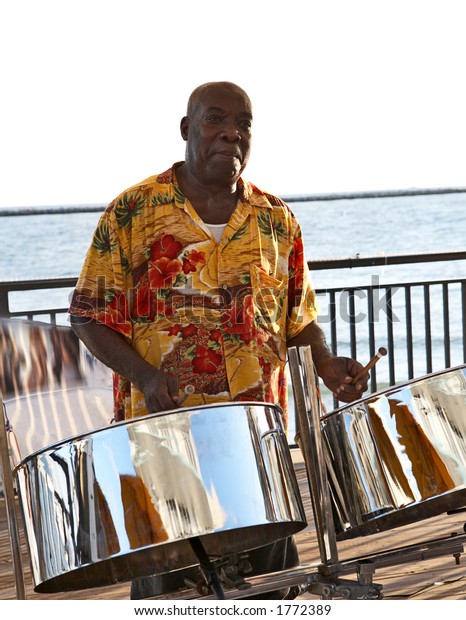 A caribbean\
musician playing steel drums.