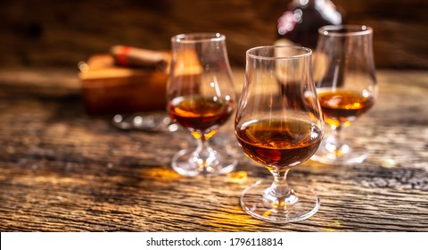 Caribbean rum in modern glasses with a bottle of rum and a cigar in the background.