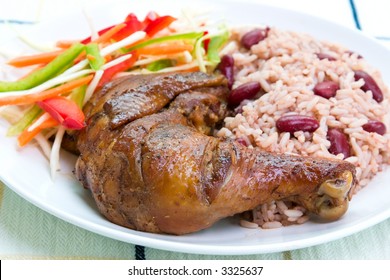 Caribbean style jerk chicken served with rice mixed with red kidney beans. Dish accompanied with vegetable salad. Shallow DOF.