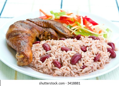 Caribbean style jerk chicken served with rice mixed with red kidney beans. Dish accompanied with vegetable salad. Shallow DOF on the rice.