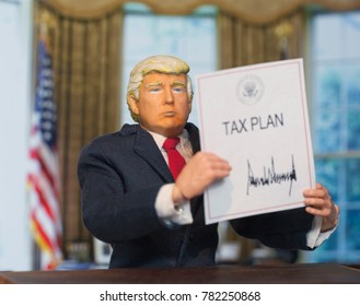 Caricature Of United States President Donald Trump Holding Up An Executive Order That States: Tax Plan, Which Was Signed As A Partisan Republican Law