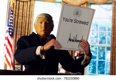 Caricature Of United States President Donald Trump Holding Up An Executive Order That States: You're Screwed - The New Tax Plan Benefits The Wealthy And Corporations Over The Middle Class