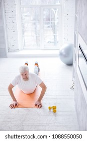 Caring About Back. The Top View Of A Pleasant Senior Man Standing In An Upward-facing Dog Pose And Stretching His Spine While Practicing Yoga