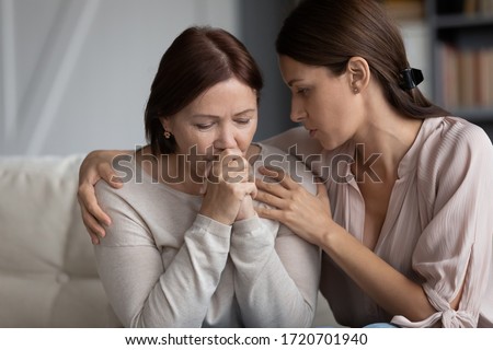 Caring adult daughter comforting soothing sad middle aged mother, holding shoulders, discussing problems, young woman hugging mature mum, expressing empathy and support, helping with troubles