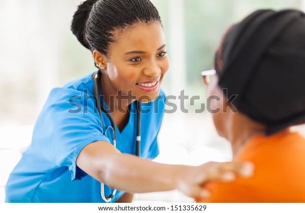 caring african medical nurse comforting senior\
patient in office