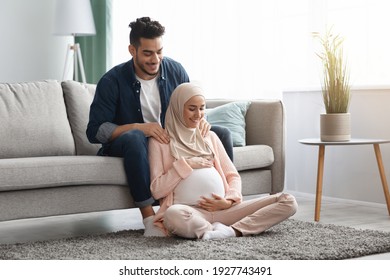 Caring arab husband making shoulder massage for his pregnant muslim wife at home, helping her relax back muscles, loving islamic family waiting baby, resting together in living room, free space - Powered by Shutterstock